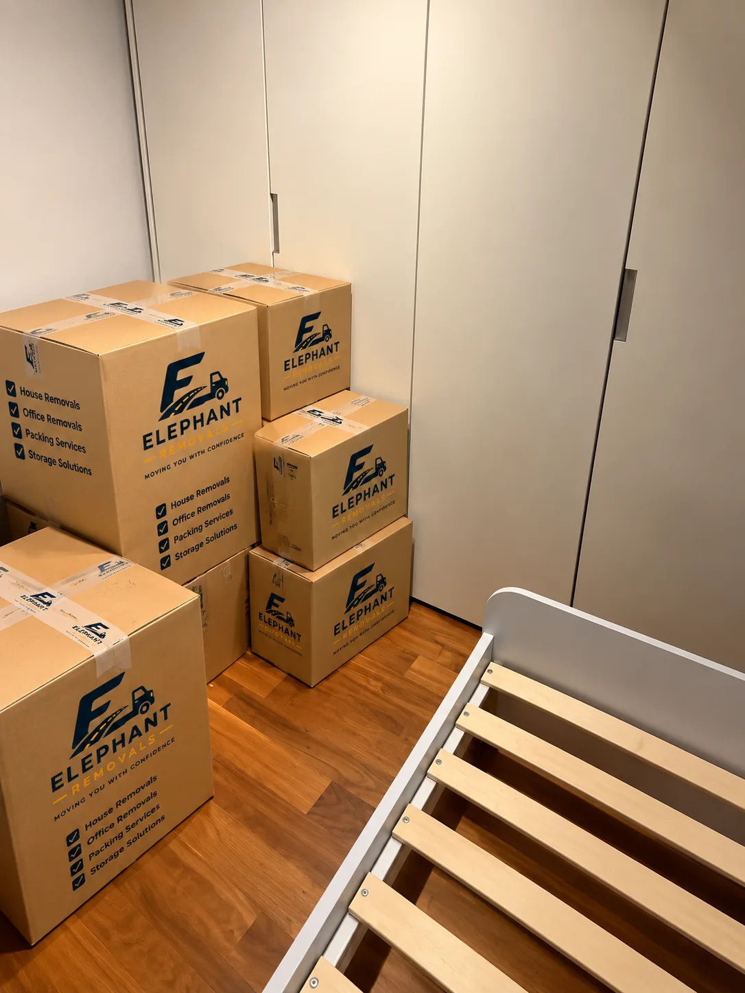 An Elephant Removals mover packing labelled boxes in a London flat